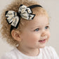 Child wearing a headband with decorative bows and text