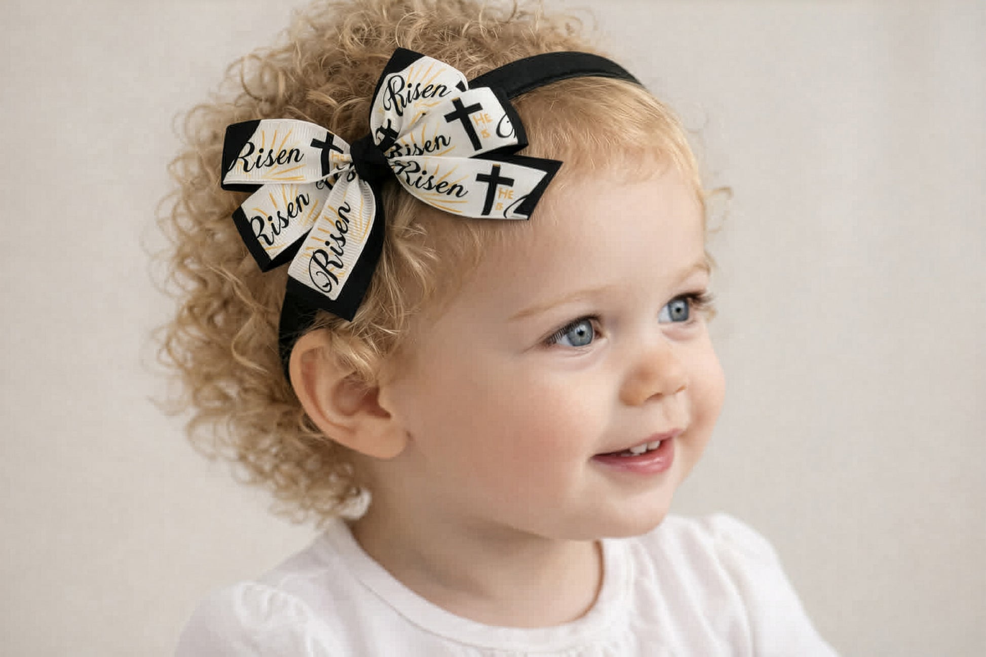 Child wearing a headband with decorative bows and text